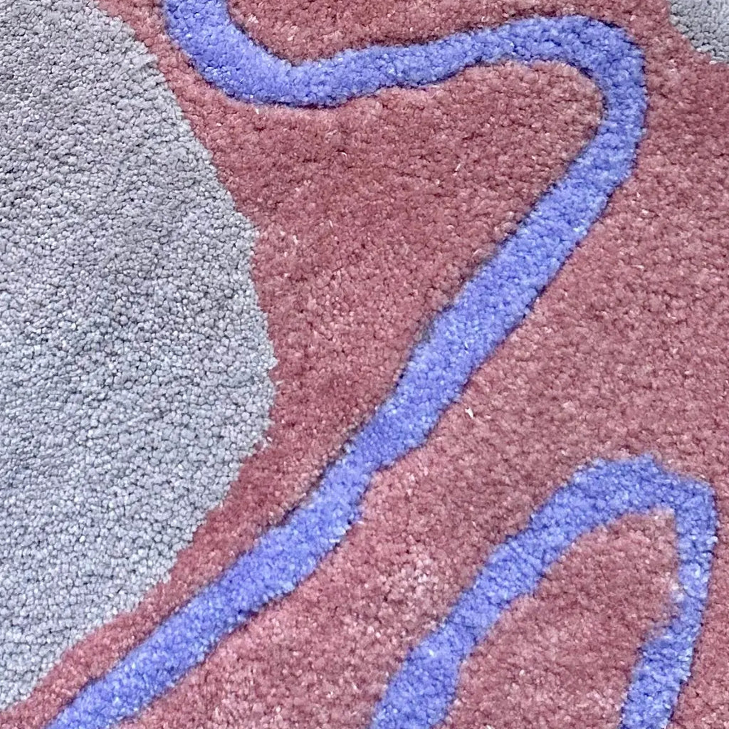 Close-up of a tufted rug with wavy purple lines on a pink and lilac background