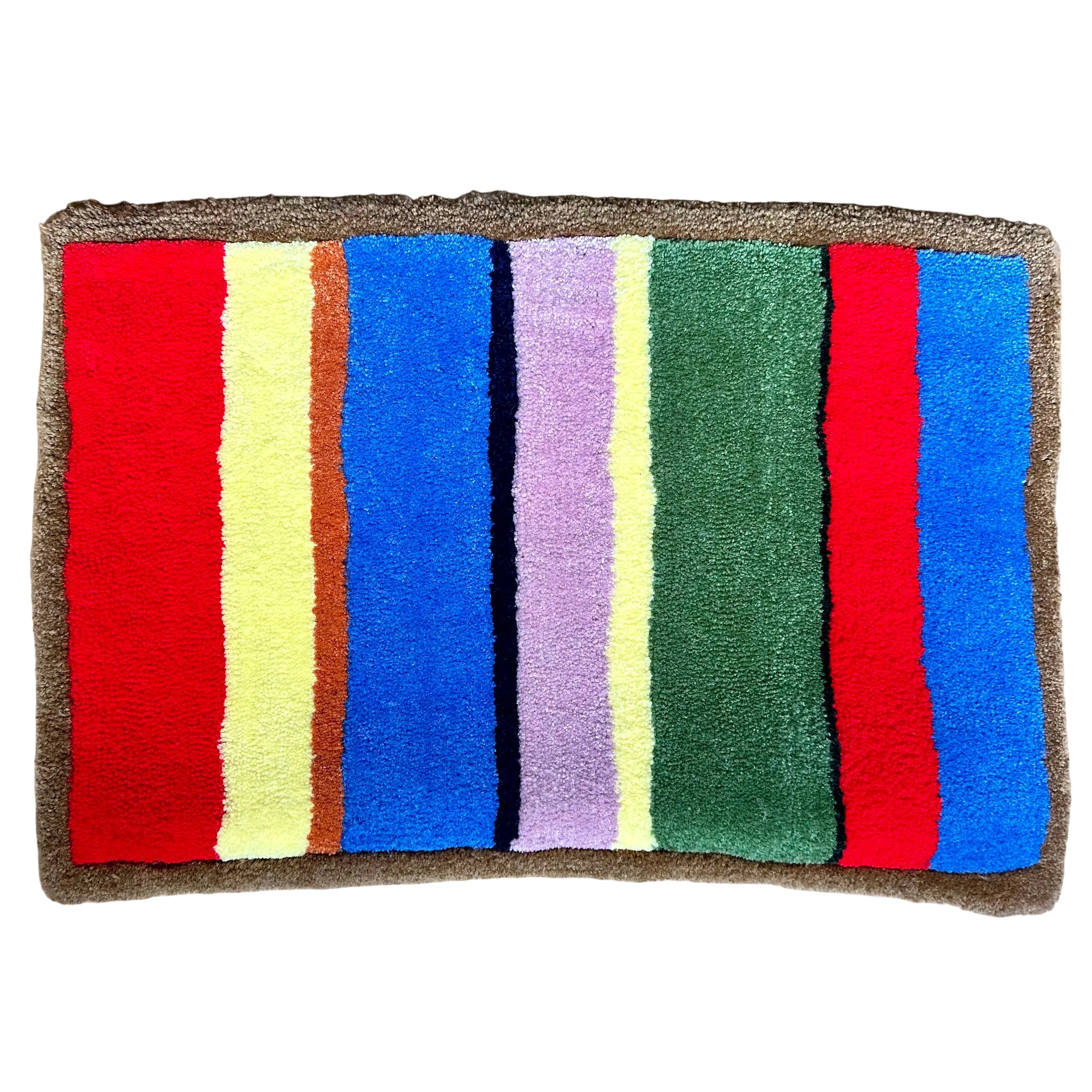 Colorful striped hand tufted rug with red, yellow, blue, pink, orange, and green stripes