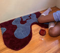 Person sitting on a colorful rug with a glass of red wine on a wooden floor.